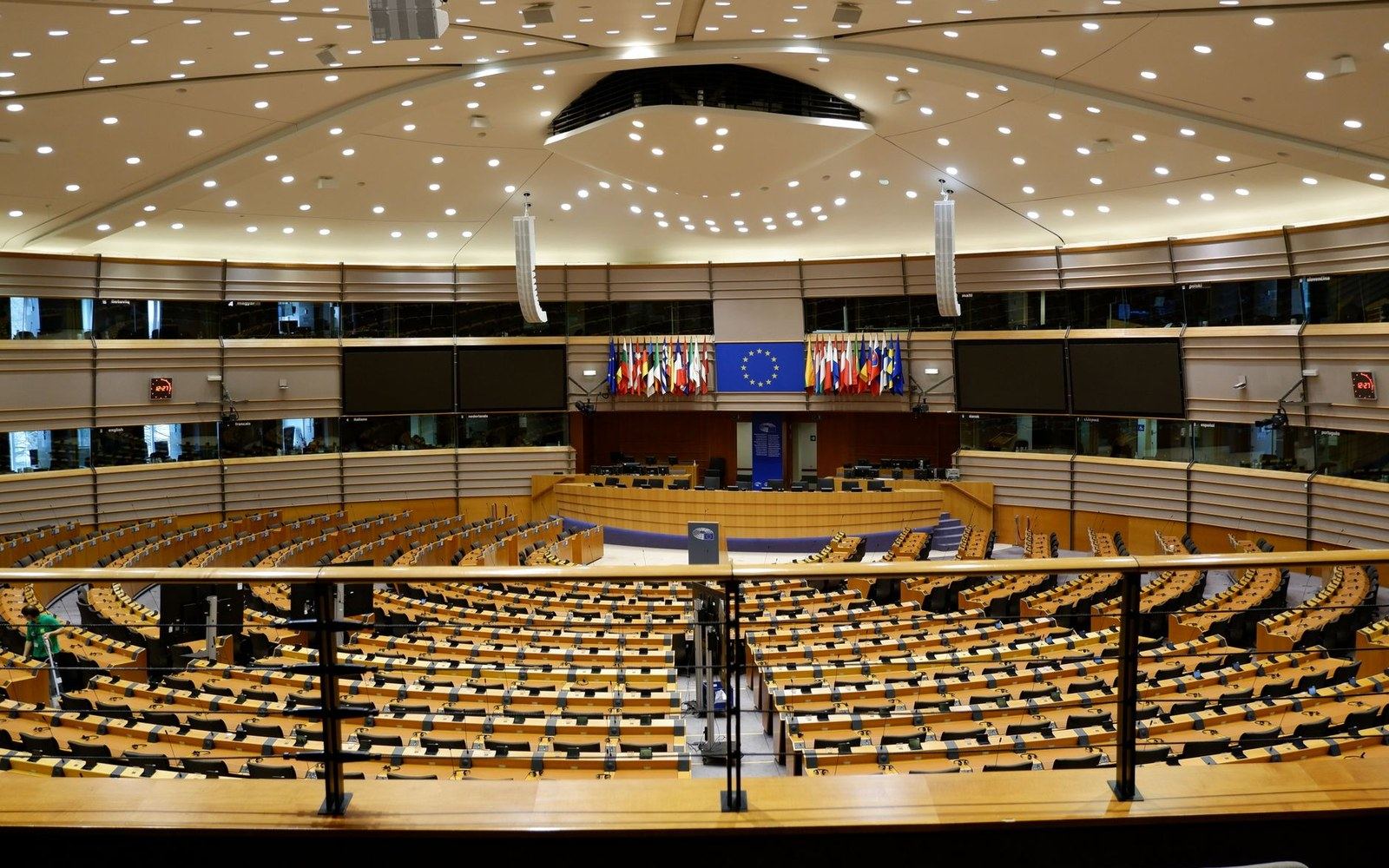 Empty rows of desks curve beneath tiered balconies in the European Parliament hemicycle