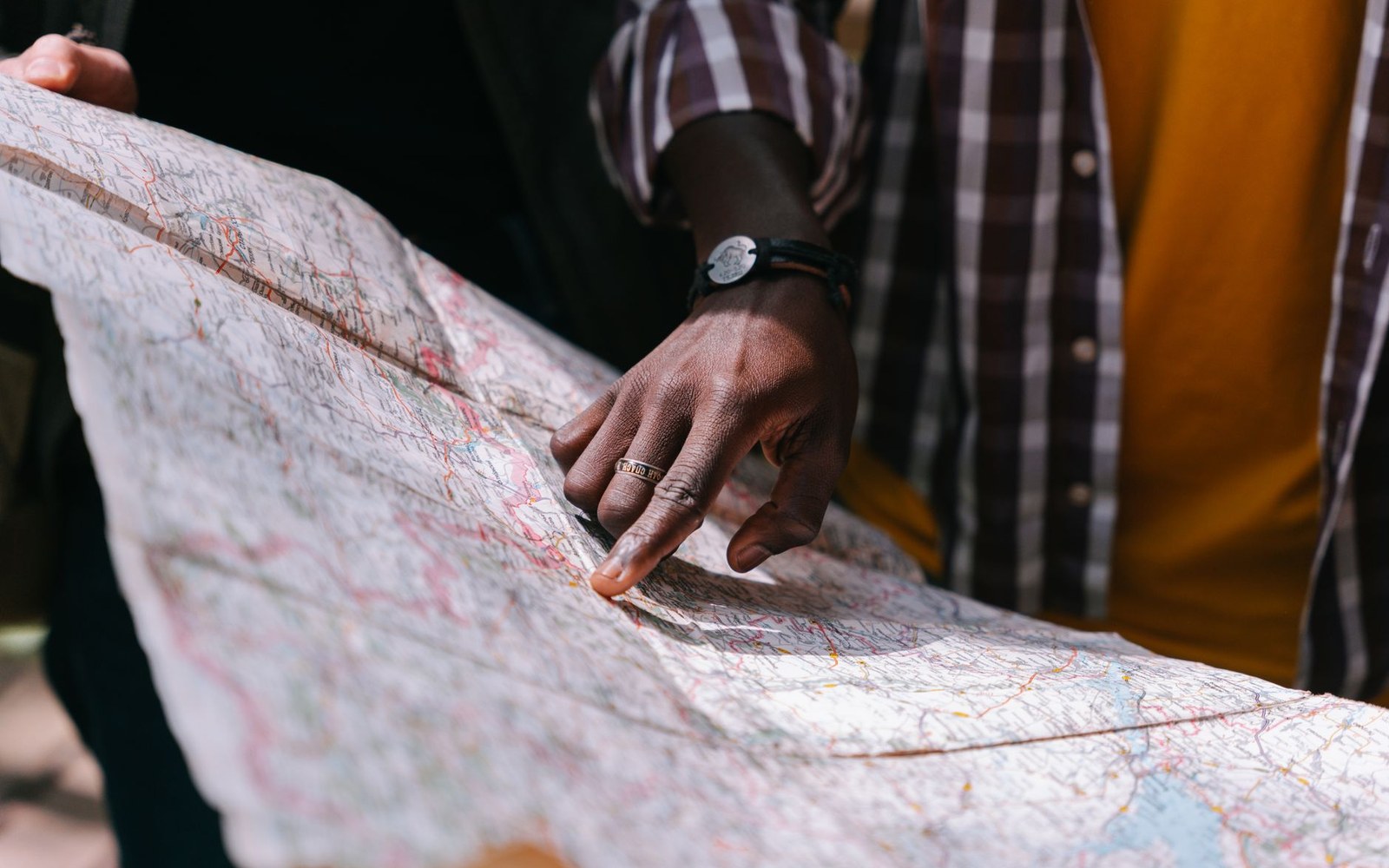 A person's finger points to a location on a folded paper road map