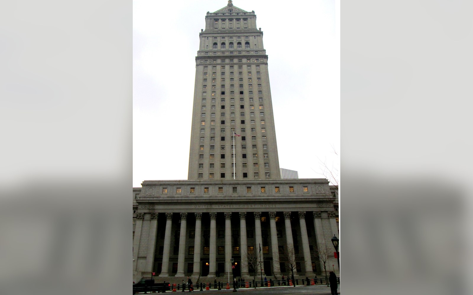 Tall columned courthouse building rises against an overcast sky in lower Manhattan