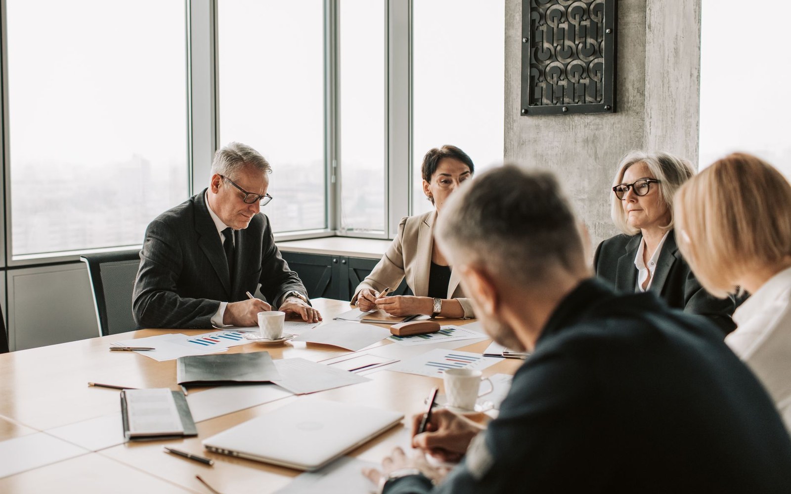 Business executives review charts and documents during a meeting at a conference table
