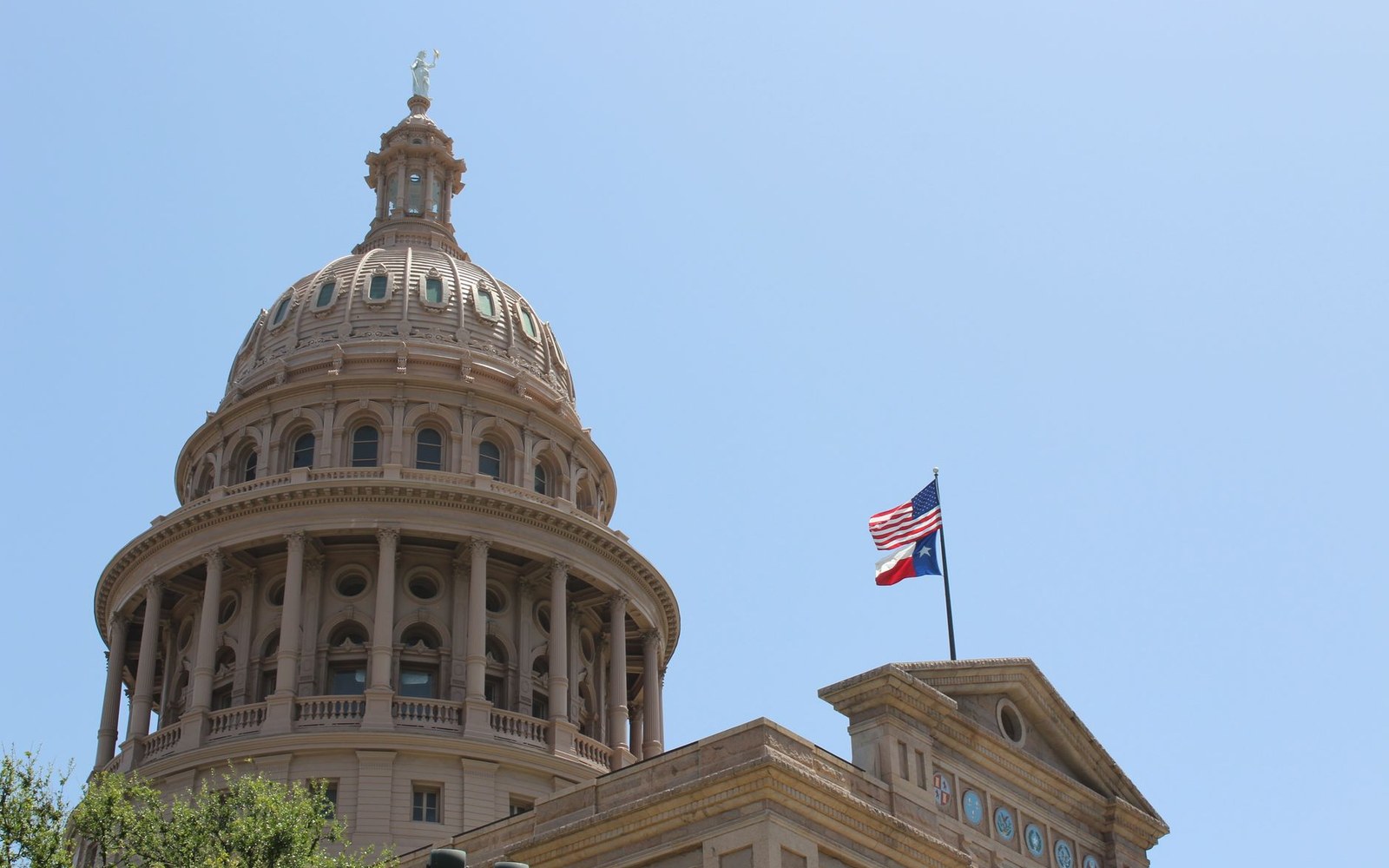 Dome of the Texas State Capitol with American and Texas flags flying atop